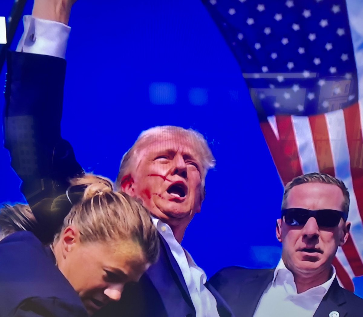 BenSwann_'s tweet photo. Absolutely Incredible: gunman attempts to shoot President Trump at his Pennsylvania rally today. Last one before the RNC convention. Trump was graced by the bullet shot directly at his face. Bloodied, the former President stood and pumped his fist in the air, shouting the word “Fight!”. President is reportedly safe and doing fine. #Trump2024
