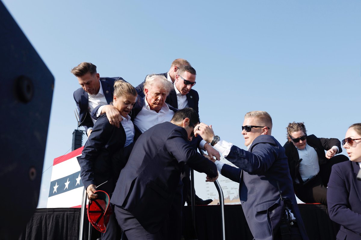 QueBuena989's tweet photo. 🚨BREAKING NEWS: Trump fue retirado rápidamente de tarima después de lo que parecieron ser disparos.

El expresidente fue escoltado a su caravana en Butler, Pa. https://t.co/l5ZwCShugm