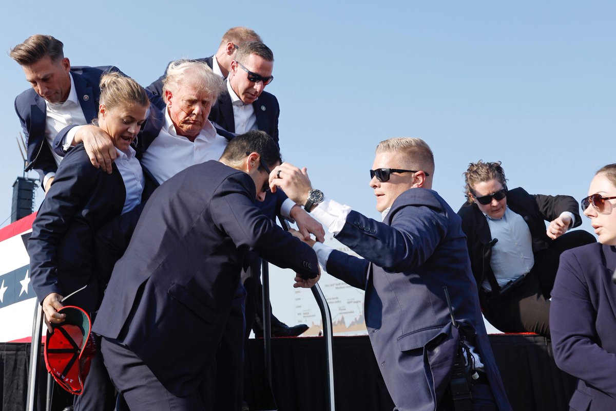QueBuena989's tweet photo. 🚨BREAKING NEWS: Trump fue retirado rápidamente de tarima después de lo que parecieron ser disparos.

El expresidente fue escoltado a su caravana en Butler, Pa. https://t.co/l5ZwCShugm