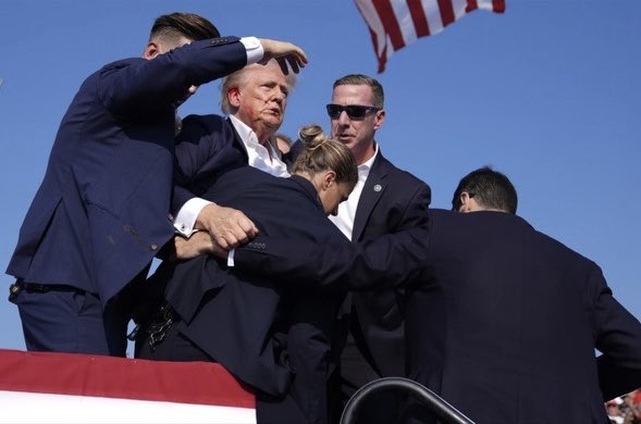 From the AP photo wire. Trump appears to have blood on his face and all over his right ear.