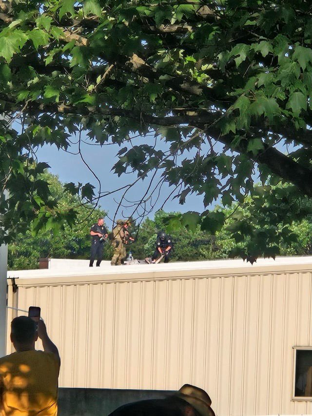 hoje_no's tweet photo. A polícia recolhendo o corpo do atirador que tentou assassinar Donald Trump durante um comício em Butler, Pensilvânia. O atirador conseguiu subir em um telhado a apenas 150 metros do palco, e apesar da polícia ter sido alertada, conseguiu disparar, falhando a cabeça de Trump por poucos centímetros.