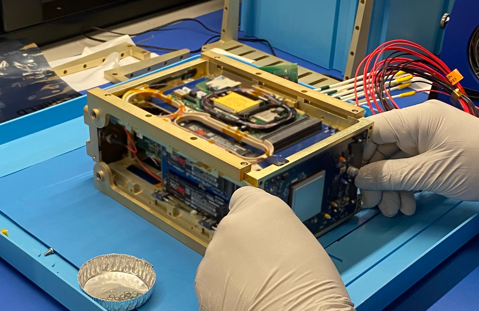 A gold rectangular box, roughly the size of a tissue box, is opened to reveal its components. 