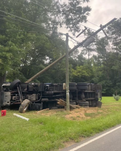 TrafficTeam9's tweet photo. UPDATE: Thanks to @DukeEnergy for this pic of the overturned garbage truck that cracked a utility pole CLOSING Idlewild Rd. east of Margaret Wallace. Crews are working to open 1 lane which will allow traffic to get by intermittently in both directions. #MatthewsNC https://t.co/TsBdLNWSUk
