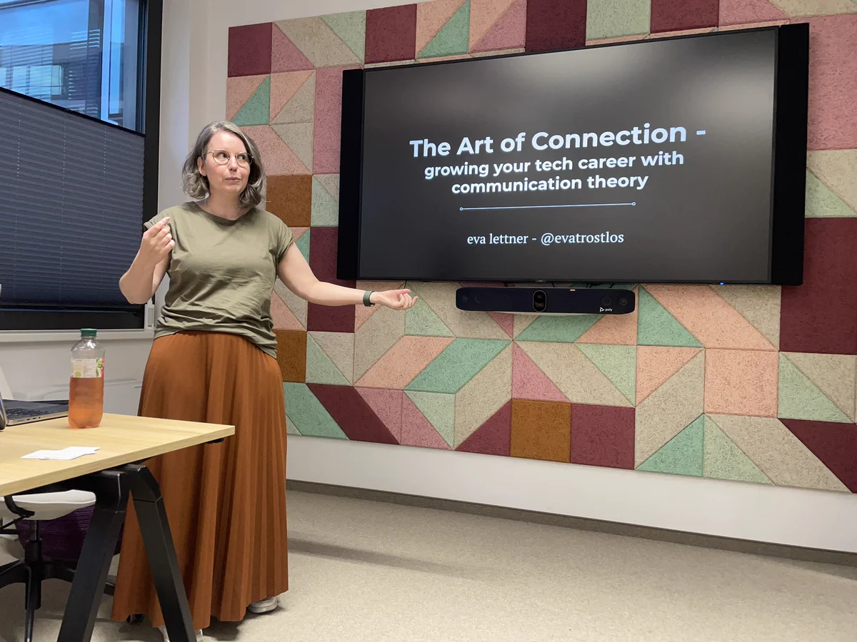 Eva on stage with the slide “The Art of communication - growing your tech career with communication theory”