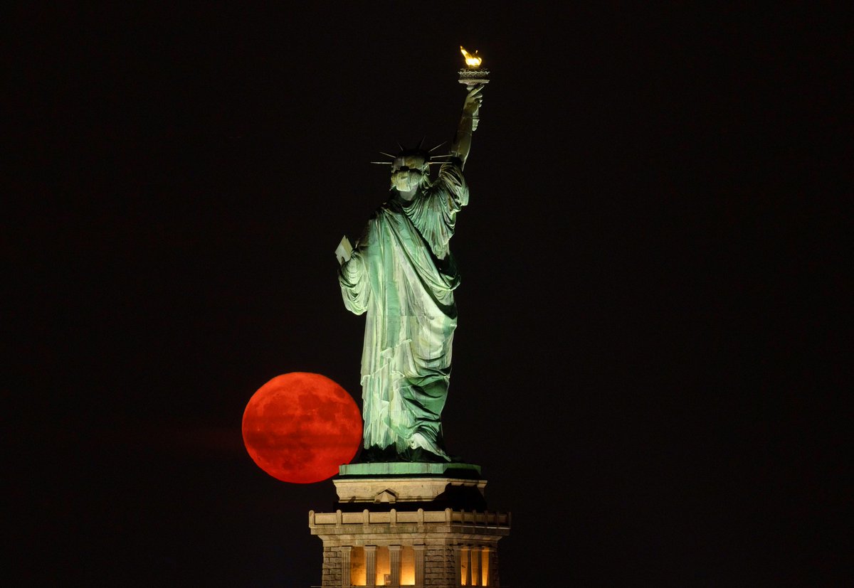 GaryHershorn's tweet image. The full Buck Moon rising behind the Statue of Liberty in New York City, Sunday evening.