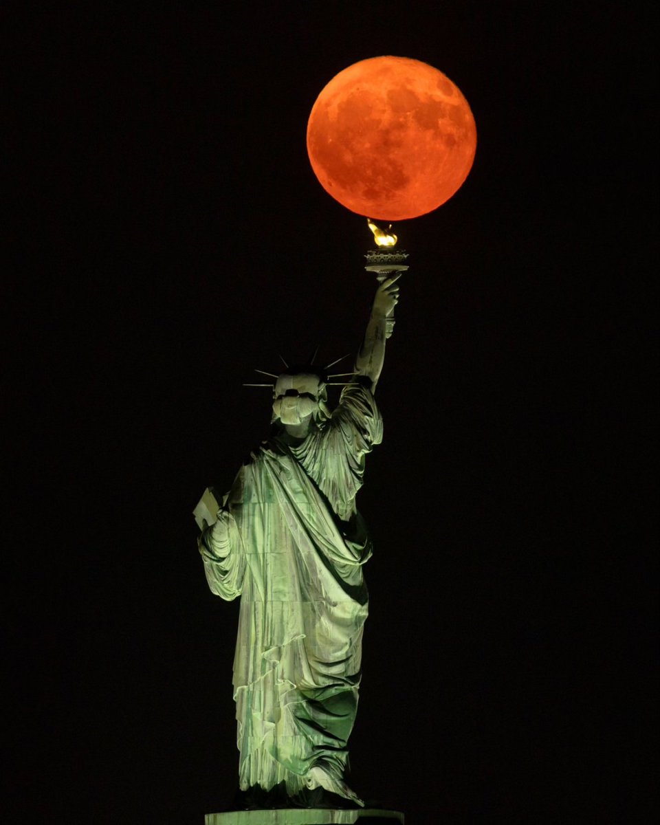 GaryHershorn's tweet image. The full Buck Moon rising behind the Statue of Liberty in New York City, Sunday evening.