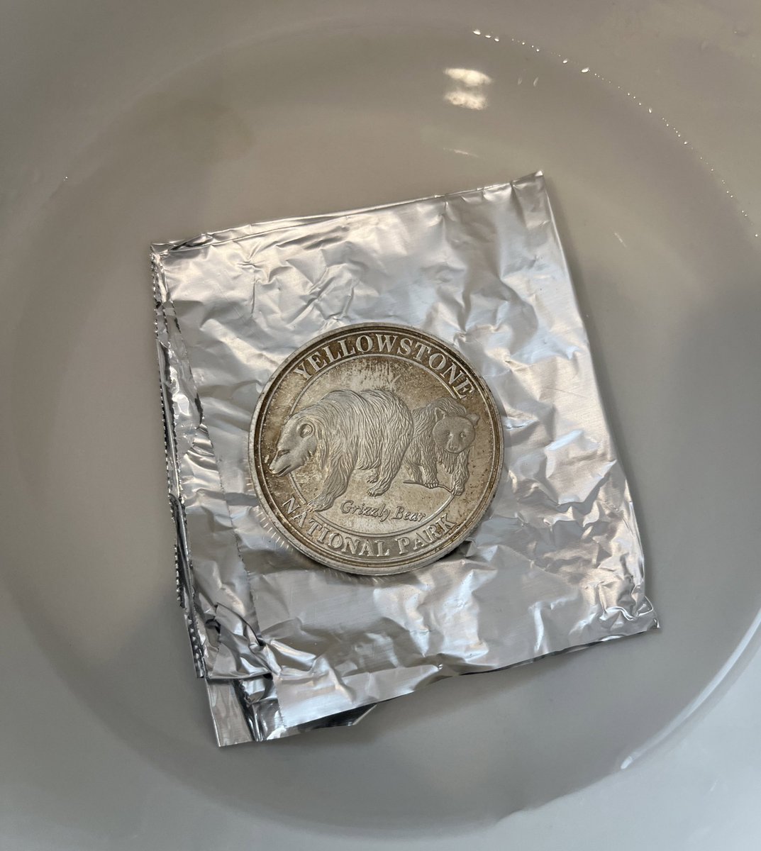 XQDavidHuang's tweet photo. My lovely Yellowstone coin turned dark because of the silver sulfide formed at its surface. A piece of aluminum foil and some salty water makes it shiny again. Not perfect thought likely because it's not made of pure silver. One of my favorite daily-life chemistry https://t.co/Ke6mo9sWqB