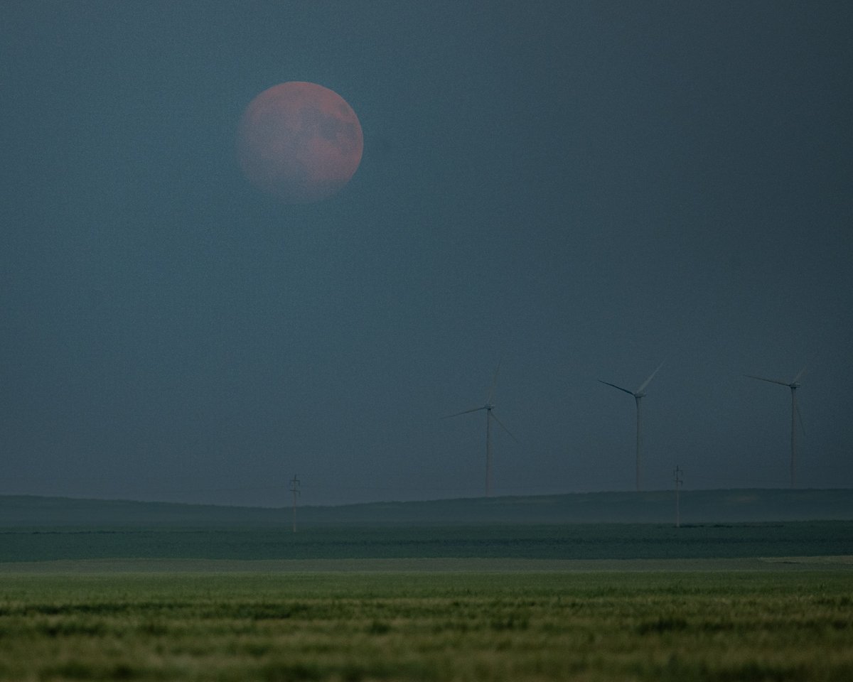 Moon finally appearing through the haze and cloud about 15 minutes after moonrise.  Barley and wind turbines in the foreground.