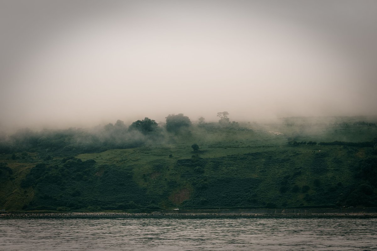 Sailing next to #NorthernIreland on the #sea can feel mystical, the #clouds roll down the hills becoming #fog and cover above while seeing vehicles and people seemingly move on the coast look like they're trying to stop being enveloped by it.

#Photography #Landscape #Nature