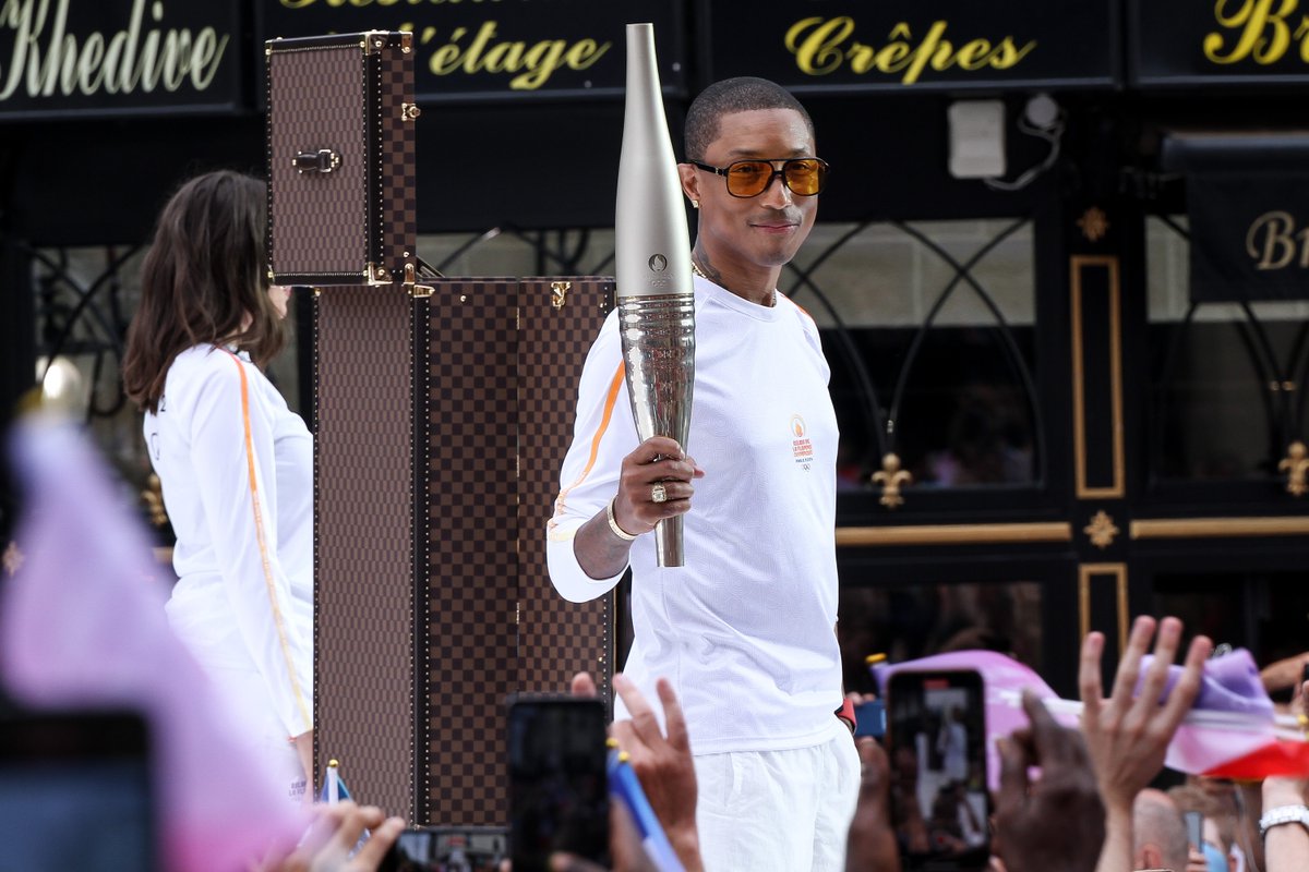 voguemagazine's tweet photo. The 2024 #Olympics just got hotter. For the final stage of the Torch Relay in France, Louis Vuitton’s Men’s Creative Director Pharrell served as the torchbearer, carrying the Olympic Flame Paris 2024, at the Basilica of Saint-Denis. https://t.co/qyqE3xhQEP https://t.co/G3nfYJ8rFE