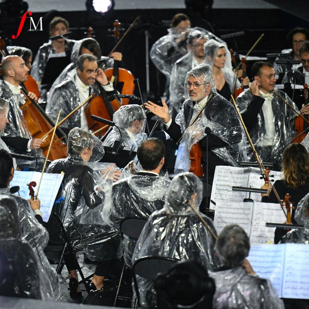 ClassicFM's tweet photo. Music in the rain. ☔️

Members of the French National Orchestra wore rain covers as they  the Olympic Hymn at the Trocadero, during the #OpeningCeremony of the Paris 2024 #Olympics. https://t.co/vmDB9g1Ve1