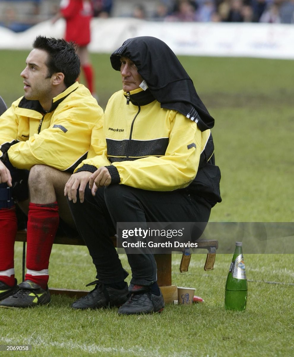 British singer Rod Stewart shelters from the rain at the BT Music Industry Soccer Six tournament held at Stamford Bridge, Chelsea FC, London (2002)