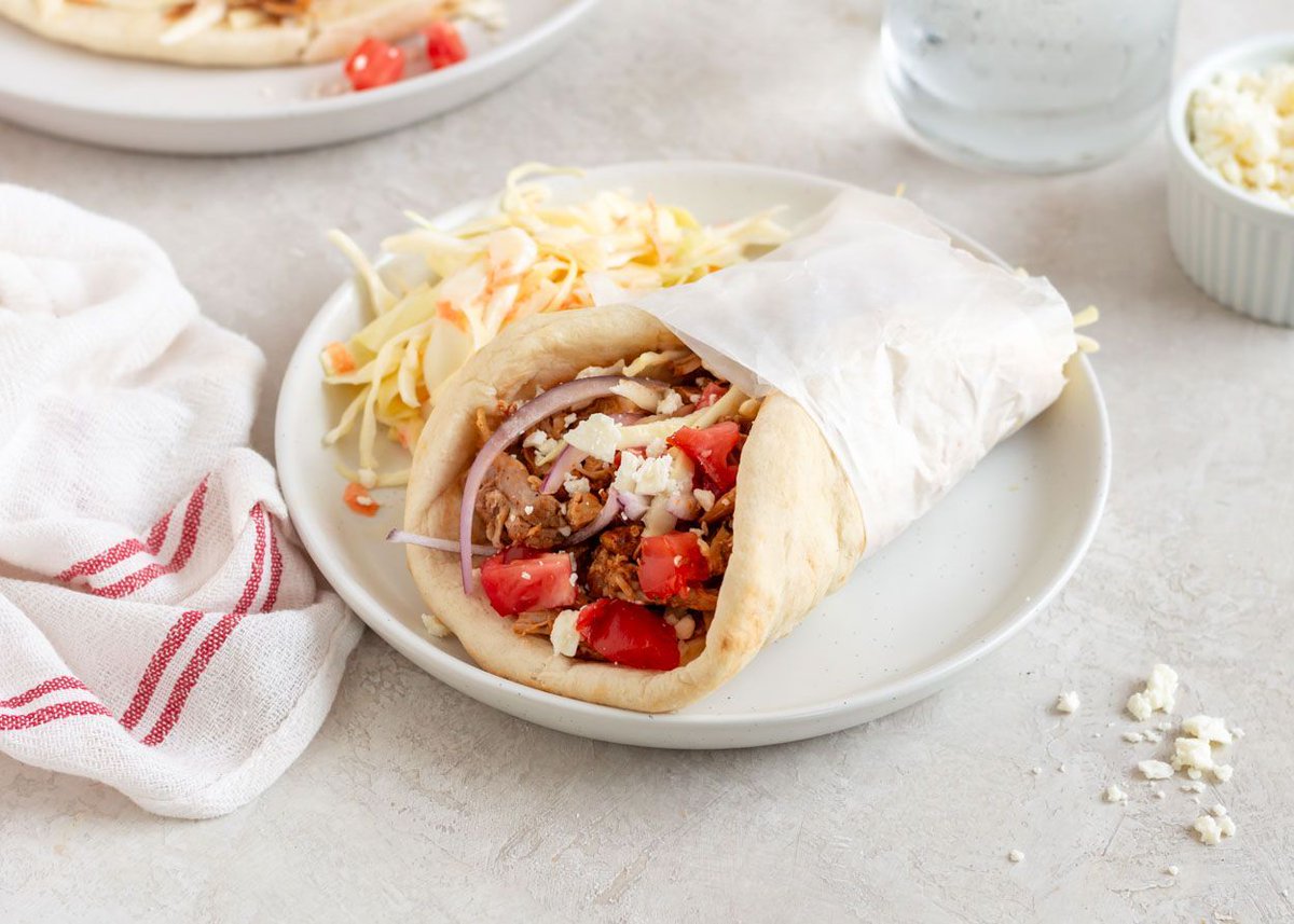 Slow Cooker (or not) Pulled Pork Gyros | This fusion twist on traditional gyros uses Tex Mex-spiced pork for the filling and creamy cabbage slaw for crunch. Top them with tomatoes and red onions for a nod to the original. | buff.ly/3LIINIF #nowcooking