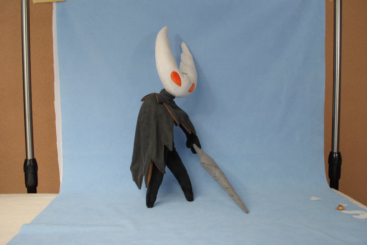 The Hollow Knight plushie that I prototyped is available! I made an earlier version that more closely represents the boss from the base game. They had a hunched posture, orange eyes, and a pustulating wound in place of an arm. The final version is more like the Pure Vessel form.