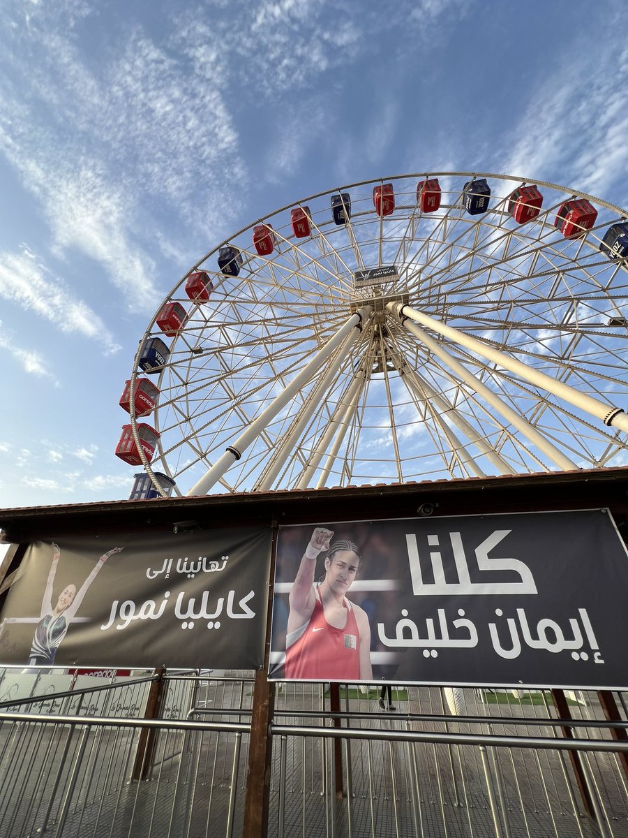 raoufbeingmoor's tweet photo. A large printed banner hanging under the 🎡 of #Algiers shows solidarity with Imane Khelif and congratulates Kaylia Nemour. Many enjoyed taking selfies with it in the background. The Olympics have never been this mainstream!

@Algeria_FC 👋🏼 https://t.co/jFykCBRWNQ