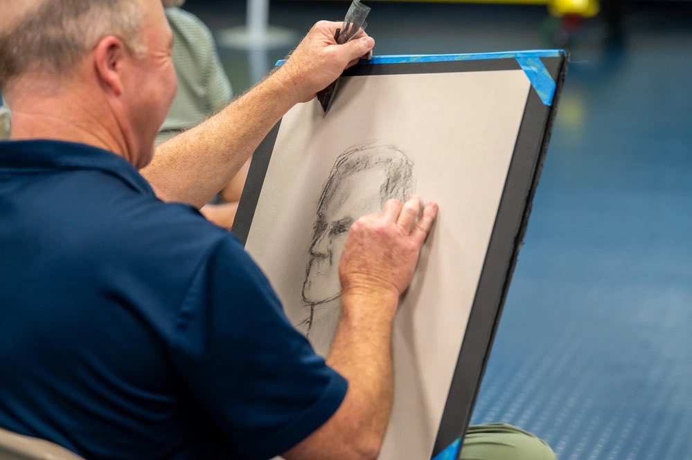 John Clark, left, Department of the Air Force Art Program artist, interviews U.S. Space Force Col. Nick Hague, center, NASA astronaut, as Marc Poole, right, a DAF Art Program artist, sketches Hague's portrait in the Sands Space History Center at Cape Canaveral Space Force