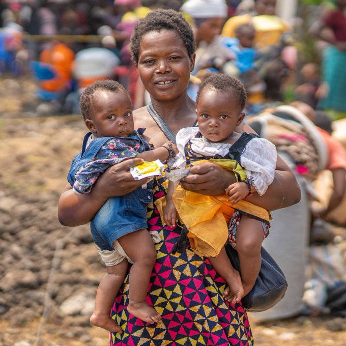 An internally displaced mother of eight stands outside a WFP distribution point in the Democratic Republic of Congo with two of her children after receiving cash and essential nutritional supplements to fight malnutrition.