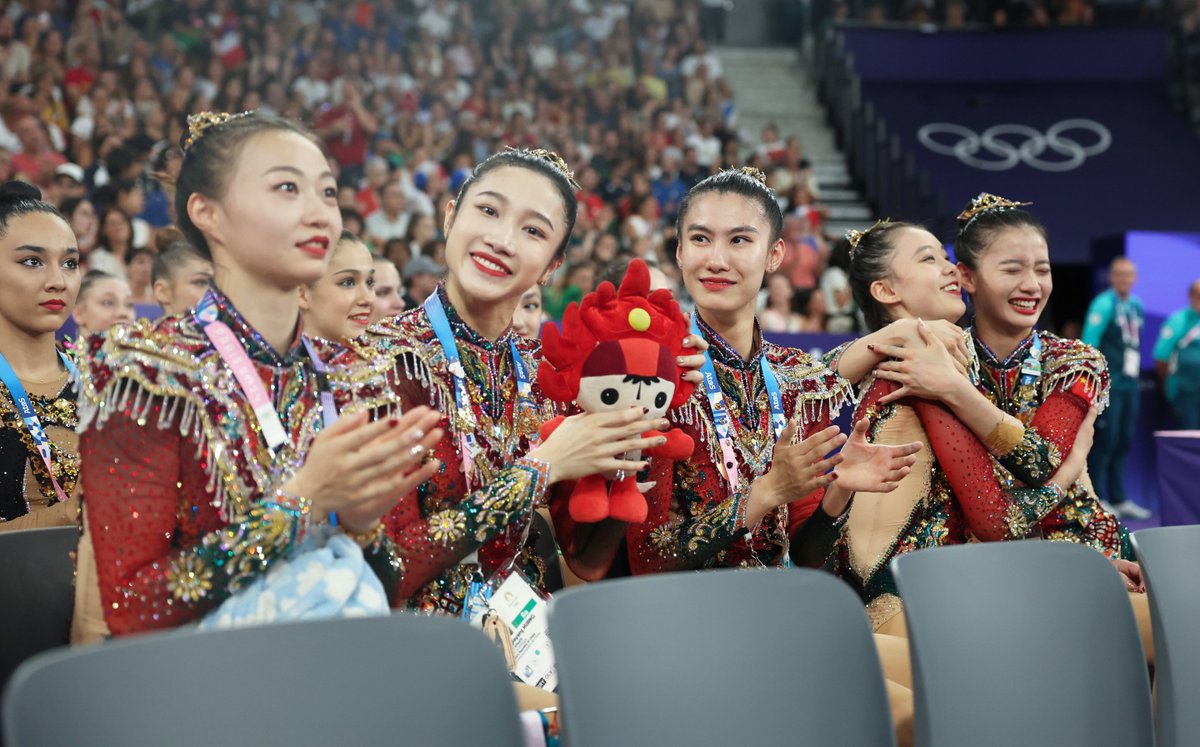 ChinaDaily's tweet photo. So adorable! One of the mascots of the 2008 Beijing Olympics, "Huanhuan", the Fire Doll, is held by the rhythmic gymnastics girls. #Olympics #Paris2024 #TeamChina https://t.co/m0thwZq7F4