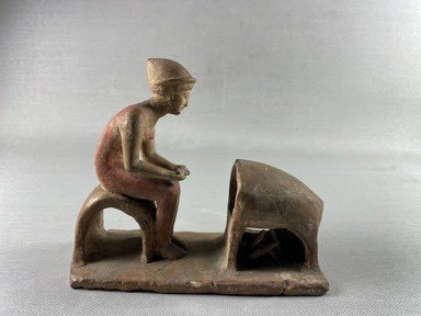 An Egyptian figurine of a woman baking bread. And not, as I first thought, a little elf watching TV.