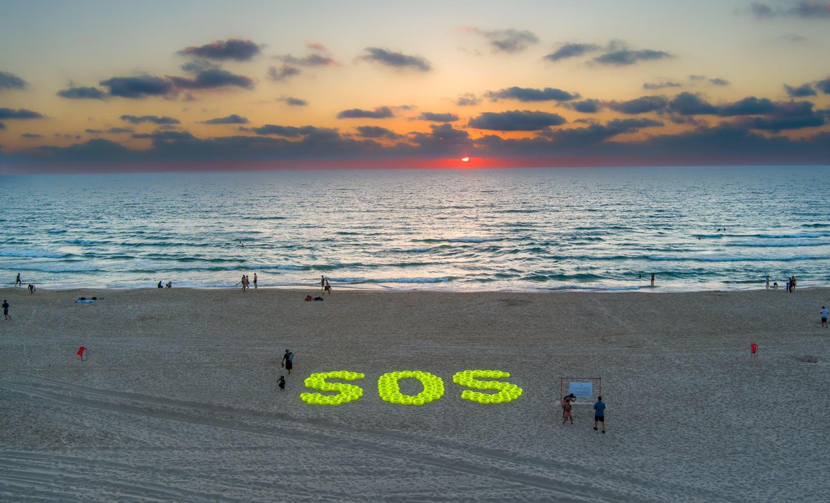bringhomenow's tweet photo. Family of Manny Godard Creates Powerful Display on the Beach Where He Grew Up: "We Wish We Could Throw a Life Preserver to Each of the Hostages".

Two days ago we marked the birthday of Manny Godard, who was murdered on October 7th in his home in Be'eri along with his wife Ayelet. His body is still held captive in Gaza.

Manny spent his childhood on the beach in Bat Yam alongside his father, who was a lifeguard there. This is where Manny's love for the sea began. Over the years, Manny became a lifeguard on Israel's beaches, saving many lives during his career.

The display includes 115 yellow life preservers symbolizing all the hostages - those alive, murdered, and fallen. The life preservers are inscribed with the word "Help" in various languages, collectively forming the acronym SOS.

Photo credit: Yair Palti