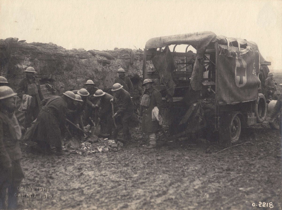 Soldats d'un bataillon canadien de pionniers (chargé des travaux de construction et de génie) comblant un trou d'obus à côté d'une ambulance endommagée lors de la bataille de Passchendaele (31 juillet - 10 novembre 1917).