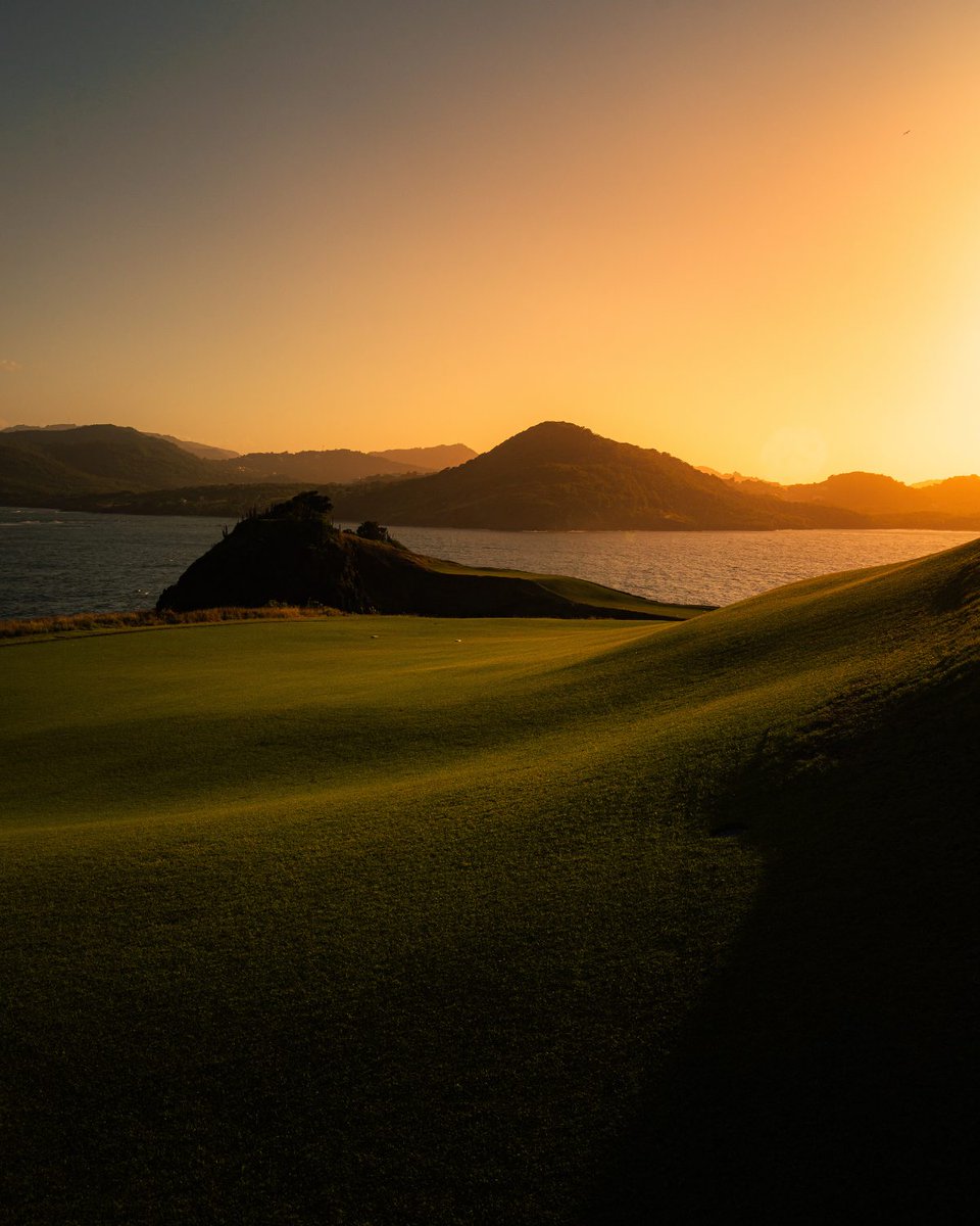 Fiery hues of orange, pink, and gold paint the sky, casting a warm, dramatic light over the 17th green at Point Hardy Golf Club. 

📷: Shawn Michael Marcellin