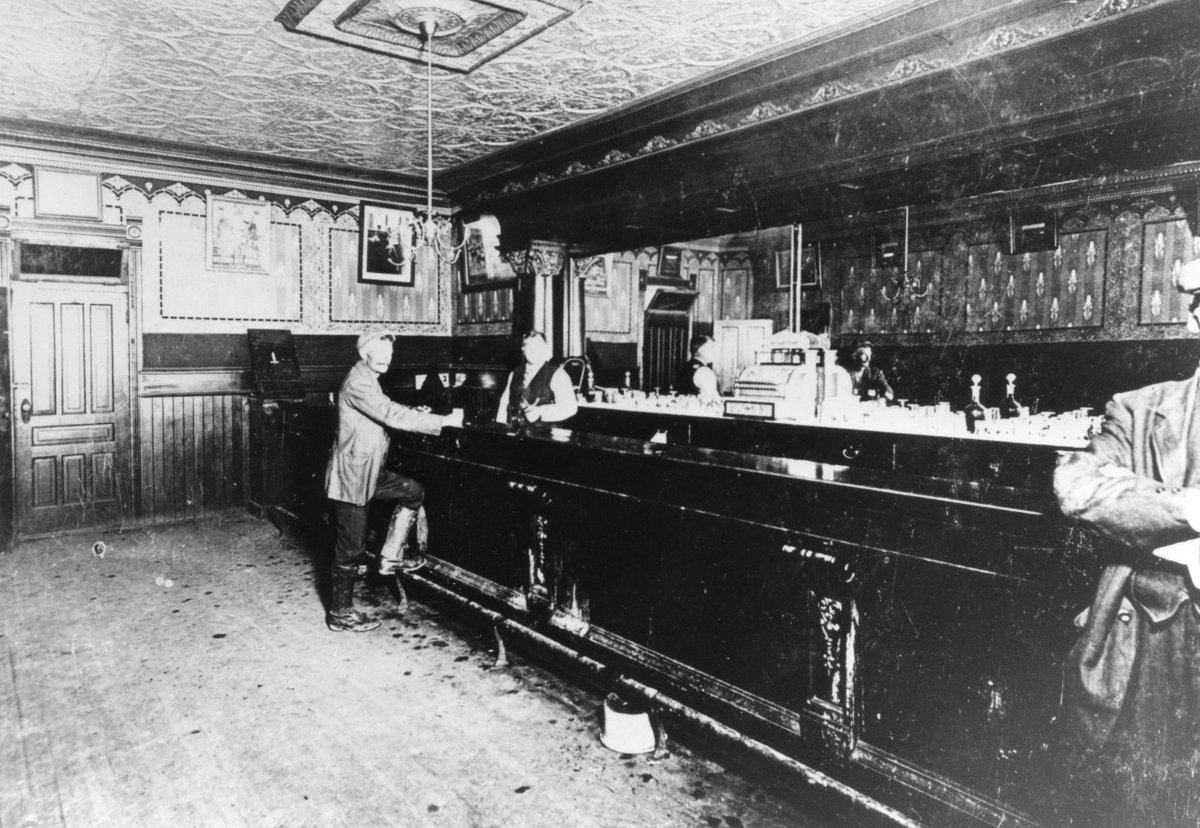 ProvArchivesSK's tweet photo. This #TBT photo of a small-town hotel bar is Moosomin’s Hotel Grand bar circa 1910 (R-A19041(1)). Using the large mirror, it is possible to gauge the size of the bar. With no chairs, a bar would not need as much space. There is less covering the floor…and the mess upon it! https://t.co/T31FOhqnsa