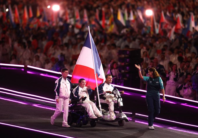 Flag bearers Aurelie Aubert and Tanguy De La Forest of Team France proudly lead the parade during the Closing Ceremony at Paris 2024, waving to the cheering crowd as they celebrate their home Games.