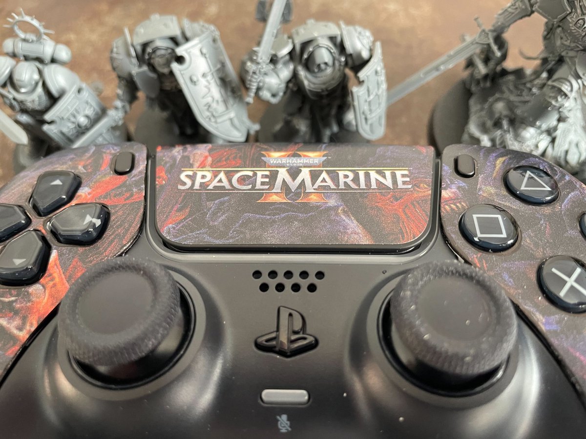 TechRaptor's tweet photo. Look what just blasted in via homing beacon! And it comes painted! Thanks to GW for sending us this Space Marine 2 PS5 controller, one less Space Marine item on our gray plastic pile of shame! #SpaceMarine2 #WarhammerCommunity #WarhammerMerchStore https://t.co/gzYFRr9bgh