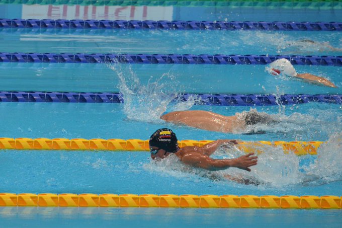 Fotografía de una competencia de natación paralímpica. Se encuentra el Para nadador colombiano Nelson Crispín avanzando con fuerza y determinación en su carril, mientras otros competidores nadan en los carriles contiguos. El agua se agita alrededor de los Para atletas, mostrando la intensidad de la competencia en la piscina.