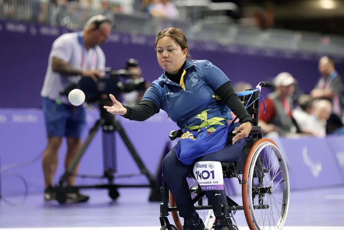 Leidy Chica lanza la bola desde su silla de ruedas durante una competencia de boccia, mostrando concentración y técnica.