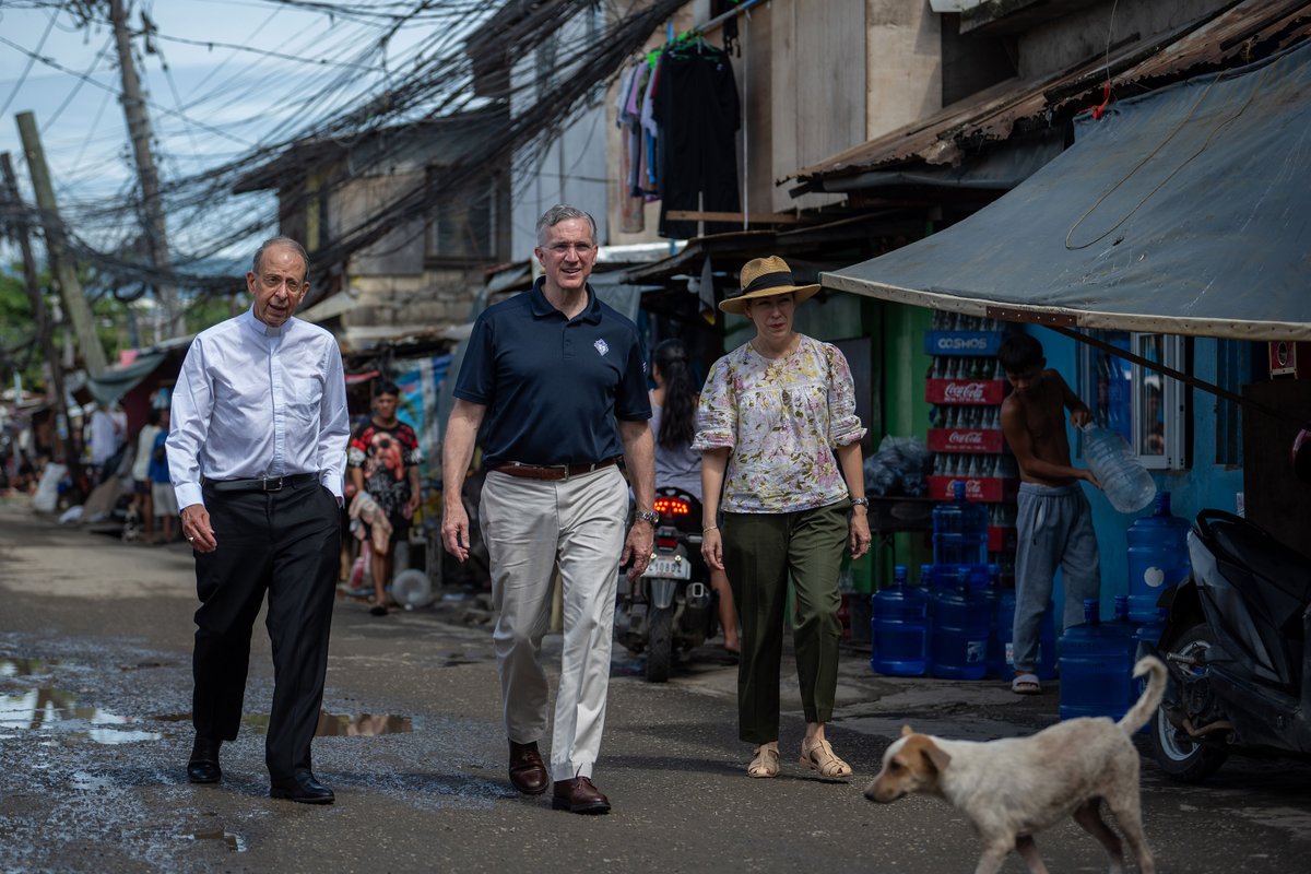 KofC's tweet photo. Supreme Chaplain Archbishop William Lori, Supreme Knight Patrick Kelly and Vanessa Kelly walk through a barangay, or neighborhood, in Cebu City, Philippines, on Aug. 26. (Photo by Tamino Petelinšek) https://t.co/PmVaqcwj8M