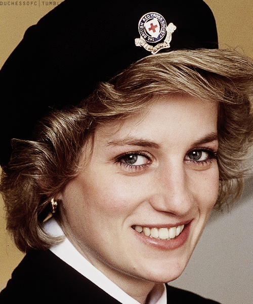 Princess Diana wearing a black beret with a British Red Cross pin. She is smiling to the camera