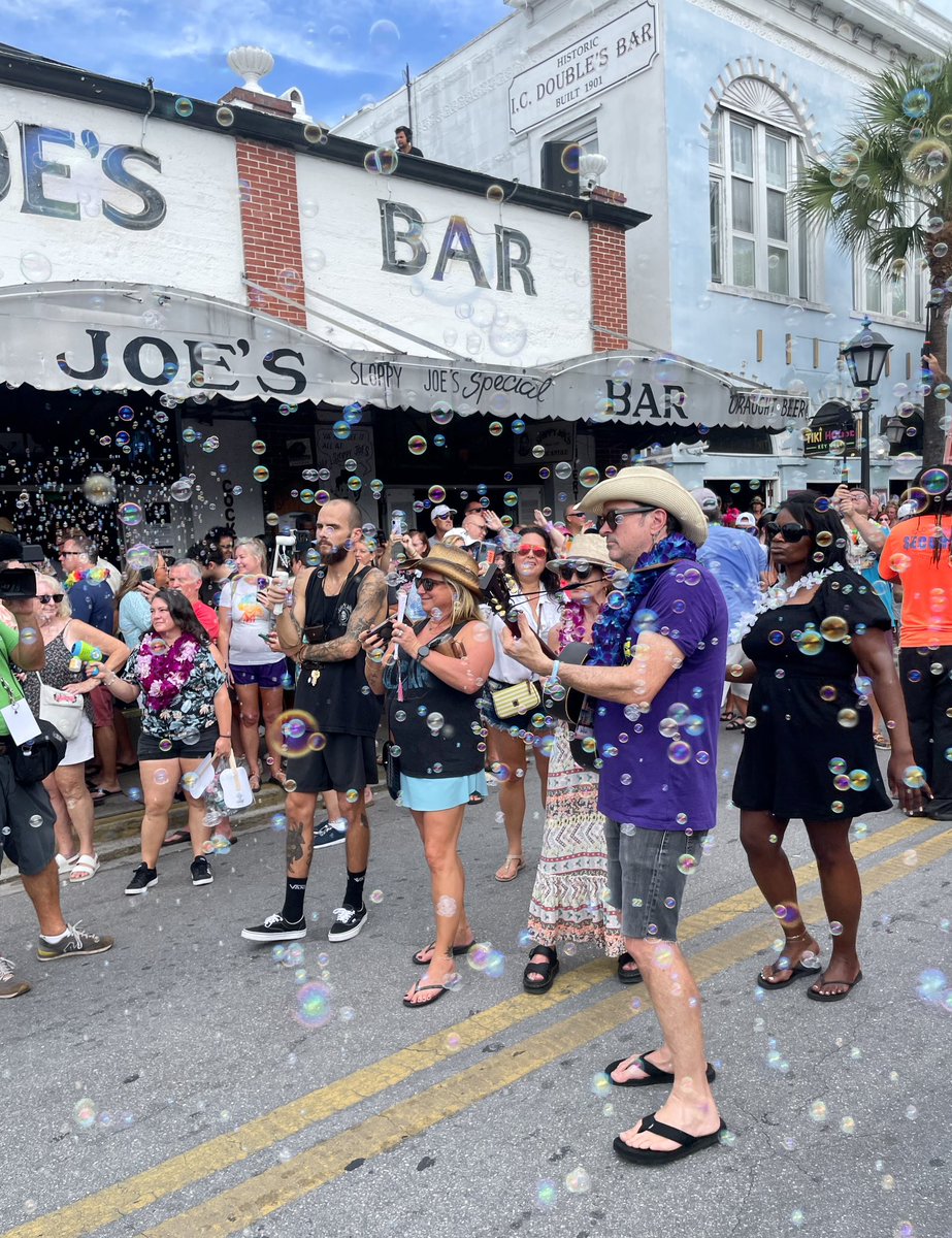thefloridakeys's tweet photo. A Second Line Memorial Walking Parade stepped off at 5 o'clock today on Duval Street in Key West, honoring the late Jimmy Buffett on the one-year anniversary of his passing. Leading the large gathering at the front of the parade was Will Kimbrough, co-writer of Buffett's posthumous hit single, "Bubbles Up" (wearing a purple shirt with guitar) as parade participants released bubbles into the air, and Keys trop rock musician Howard Livingston. They stopped the parade in front of the Margaritaville restaurant to sing the namesake song. 📷: Carol Shaughnessy
