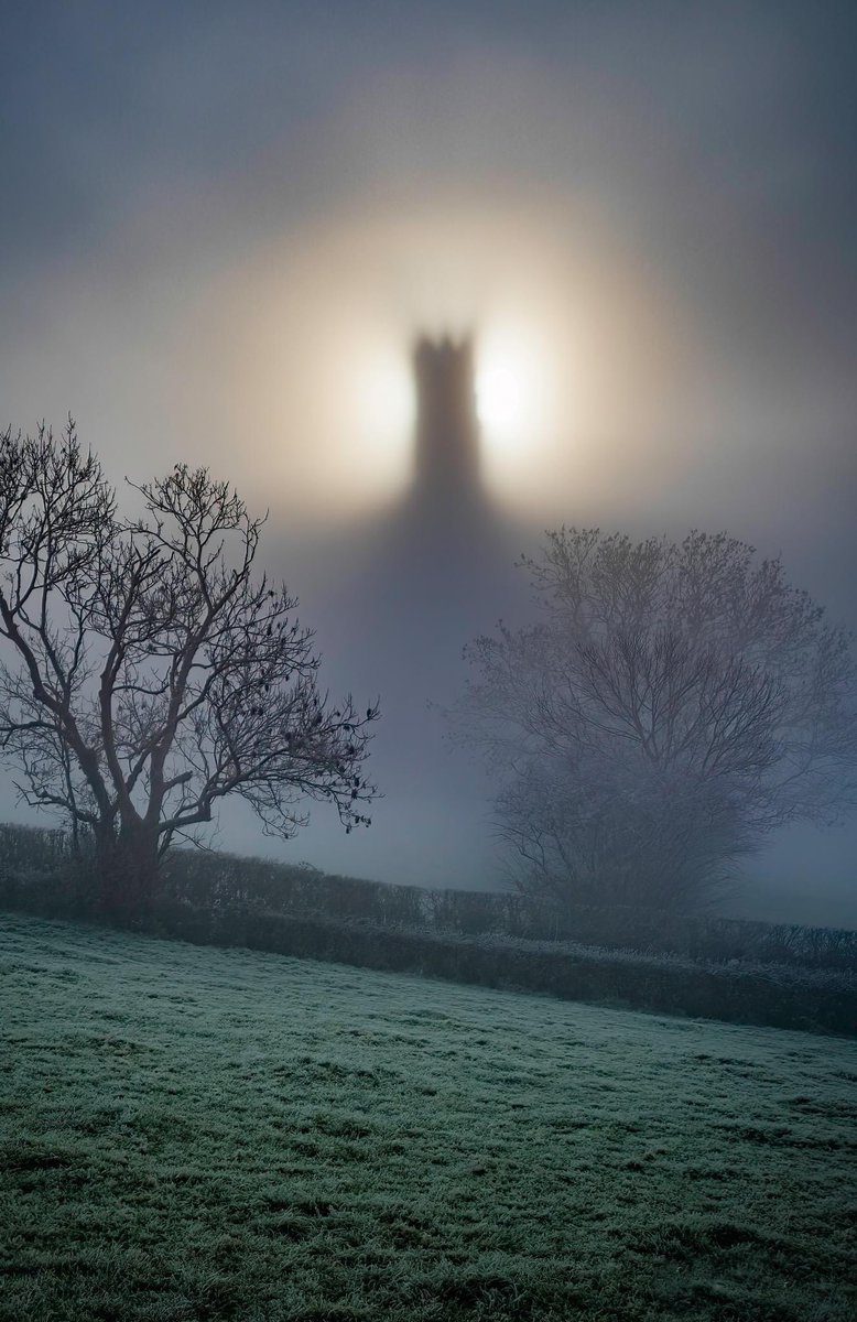 The sun behind Glastonbury Tor on a foggy morning.