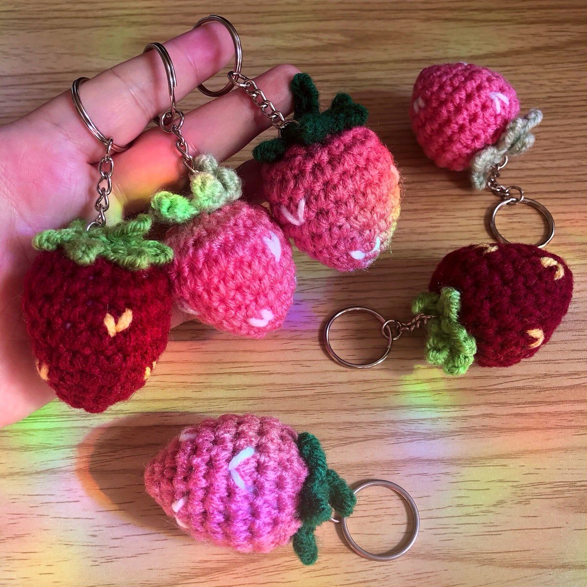 debuting these cute lil crochet strawb keychains at <a href="/ComicConHNL/">Comic Con Honolulu</a> this weekend 🍓🥰🍓 love the little rainbow spots in these pics from my suncatchers and the morning sun 🥹🌈