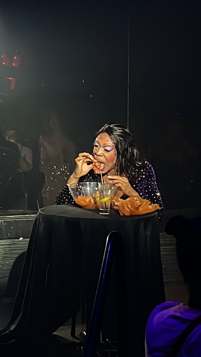 drag queen wordlessly eating a full seafood boil in the club to “under the sea”