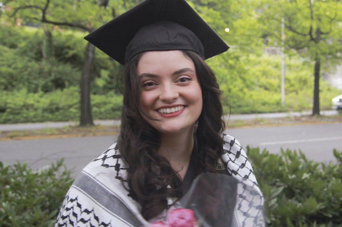 A photo of Aysenur Ezgi Eygi, a 26-year-old American activist who was killed while protesting Israel’s illegal occupation of the West Bank. She is smiling and wearing a black graduation cap. She has a traditional Palestinian keffiyeh draped over her shoulders.