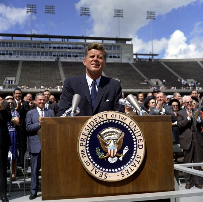 President John F. Kennedy delivers remarks at Rice University regarding the nation's efforts in space exploration. Standing in back on speakers' platform (applauding): Mayor of Houston, Lewis Cutrer; Representative Albert Thomas (Texas); Representative George P. Miller (California). Rice University Stadium, Houston, Texas. Credit: Robert Knudsen. White House Photographs. John F. Kennedy Presidential Library and Museum, Boston