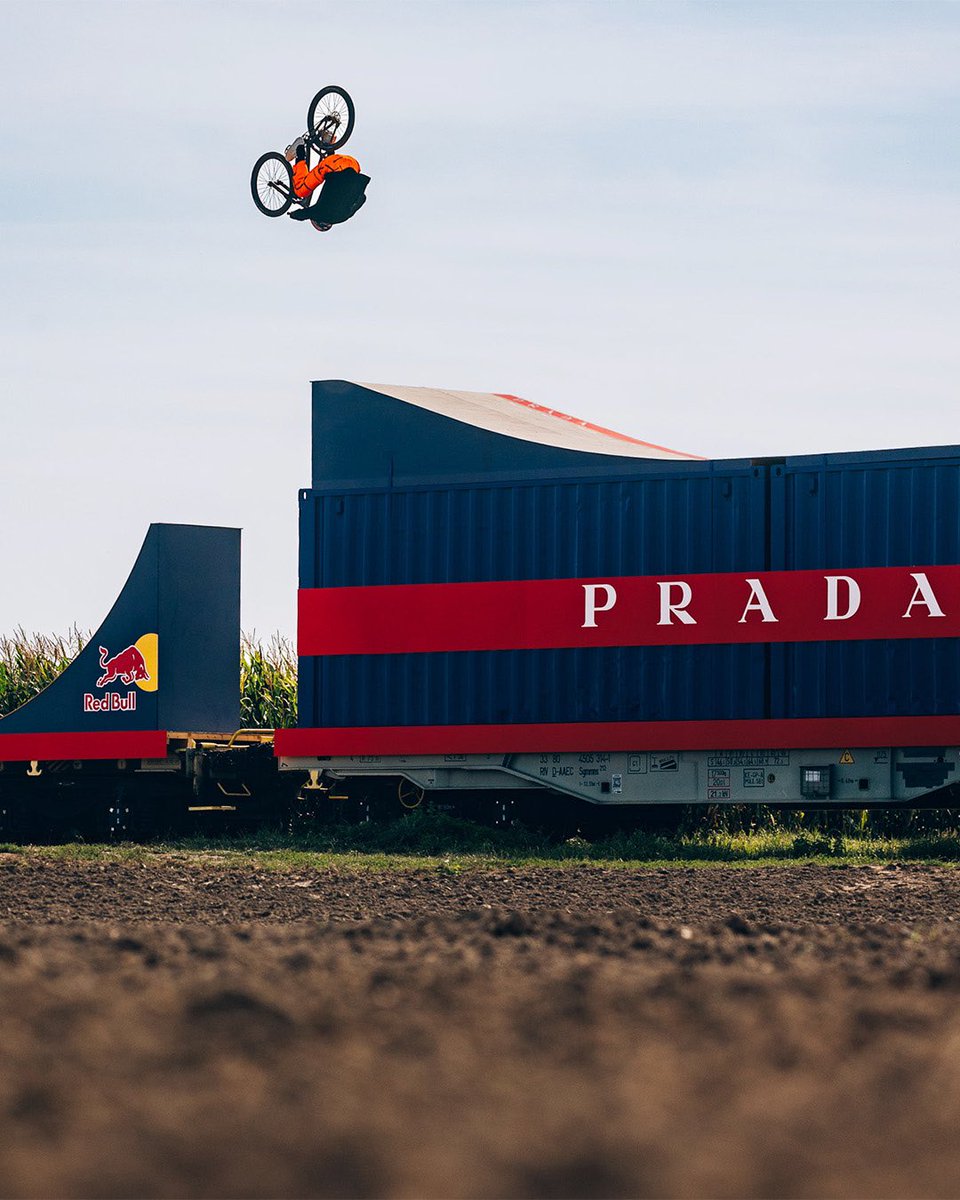 Prada's tweet photo. Prada Linea Rossa has once again partnered with Red Bull to create an unprecedented challenge. This train-bound bike course, mastered by 2024 Slopestyle World Champion Dawid Godziek, is a marvel of engineering, built on a train in Upper Silesia, Poland. It features 8 jumps, a roller, and a stair drop, resulting in the world’s first flat drop backflip to flat landing from stairs. The feat is supported by Prada Linea Rossa's ever-enhancing high-performance wear, inspired by the human body’s most athletic accomplishments.
Discover more: https://t.co/S5nNiokTwG 

#Prada #PradaLineaRossa #RedBull