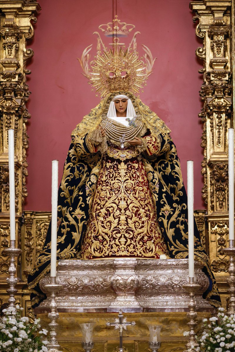 EspDeTriana's tweet photo. #ACTUALIDAD | Con motivo de la próxima visita a la Capilla de los Marineros de nuestra Hermandad hermana @HdadBaratillo por la Coronación de Nuestra Señora de la Piedad, se ha procedido al cambio de vestimenta de Nuestra Señora de la Esperanza  

Para la ocasión, luce la saya procesional bordada en oro fino sobre terciopelo granate estrenada en 2022 y realizada Francisco Carrera Iglesias “Paquili”. Prendida de la saya luce el escudo de la hermandad del Baratillo, regalo que fue con motivo de nuestro hermanamiento. 

Porta esta vez manto de terciopelo azul, diseñado por el ceramista Francisco Peláez y bordado en oro por los talleres de Fernández y Enríquez en 1998. En 2023 se enriqueció en el taller de Jesús Rosado Borja con un salpicado que alterna motivos vegetales y anclas.

Cubriendo el manto, presenta una toca tejida en oro fino en la técnica de bolillos por Alfonso Aguilar, pieza que reproduce la célebre toca de volantes que luce la Virgen en las fotos de Serrano de los años treinta del pasado siglo XX, estrenada para la Cuaresma del pasado año.