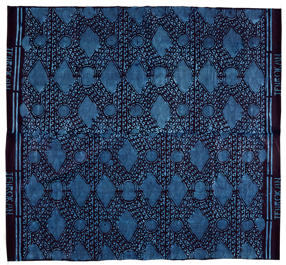 This Nigerian textile utilizes a resist-dye technique called “adire eleko.” The resist element is made from cassava flour and is painted, stenciled or combed over the cloth. After drying in the sun, this mantle was dipped in synthetic indigo, revealing the patterns.