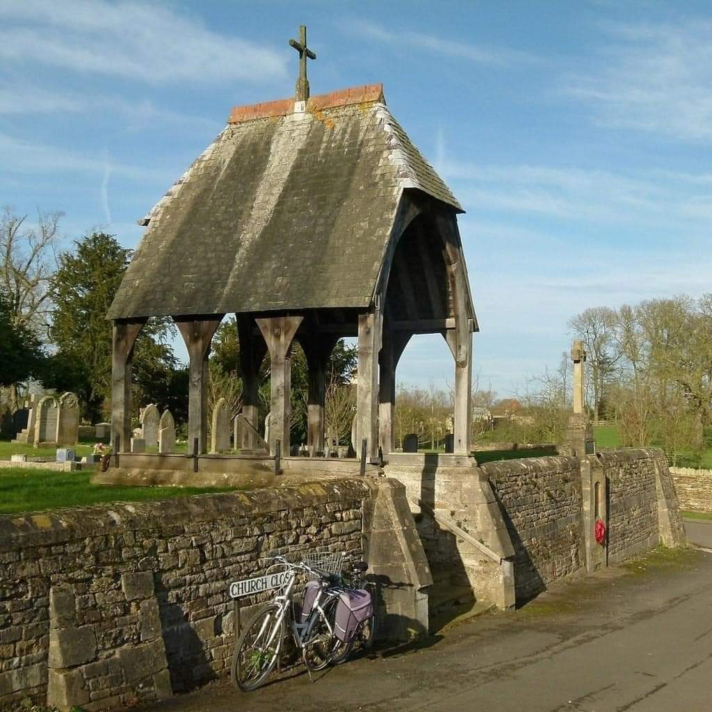 militaryhistori's tweet photo. Good morning & Happy Saturday!
During the Middle Ages, before the existence of mortuaries and when the majority of people passed away at home. When someone died, their body was placed on a bier and transported to the lychgate, a significant structure at the entrance of the churchyard or cemetery.

 There, the departed would rest, safeguarded from potential bodysnatchers, until the funeral service, which might take place a day or two later.

A Lych gate, also spelled "lodge gate" or "lich gate," is a traditional architectural structure often found at the entrance of churchyards or cemeteries in the United Kingdom and some other English-speaking countries.

The name "Lych" is believed to have originated from the Old English word "lic," meaning corpse or body, as the gate was historically associated with funeral processions and the dead.

Lych gates typically consist of a roofed structure with two side walls or wooden posts on either side, forming a narrow passageway or gateway. The gate usually serves as the main entrance into the churchyard or cemetery, and its design can vary in architectural style, reflecting the local traditions and historical periods.

The primary purpose of a Lych gate is to provide shelter for mourners and the coffin while the funeral party waits for the clergy to arrive or conducts the initial part of the funeral service. 

It also symbolizes the transition between the outside world and the sacred grounds of the churchyard, often marked with a symbolic religious significance.

Many Lych gates are beautifully adorned with intricate carvings, engravings, or decorative elements, adding to their aesthetic appeal and cultural significance. 

Over the centuries, Lych gates have become symbols of the close connection between the church and the local community, as well as a reminder of the passage of time and the continuity of traditions in rural areas.