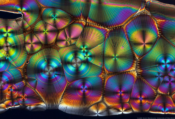 An image of vitamin C, taken with polarised light. It is colourful featuring both green, purple, blue, yellow, orange, pink, white and black.