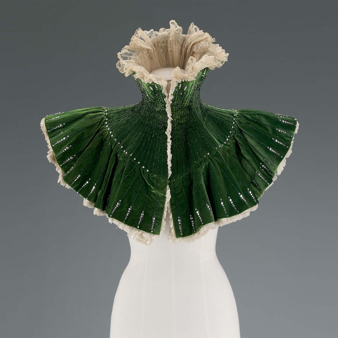 Evening mantle retailed by Le Bon Marché department store, maker unknown c. 1900.​​​​​​​​​​​​​​​​​​ Striking green velvet short mantle reflects the opulence of Edwardian fashion.   Learn more at VFG Fashion Timeline
vintagefashionguild.org/resources/fash…
Credit: MFA Boston