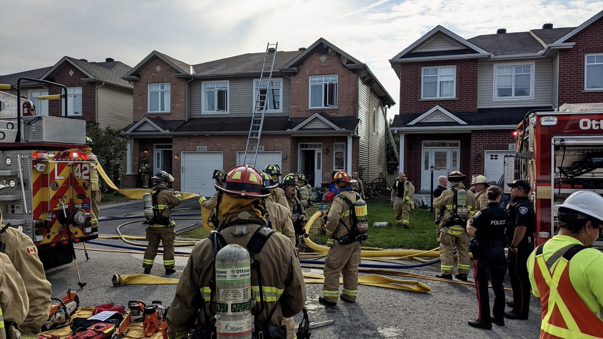 OttFire's tweet photo. Firefighters prevented a fire in a semi-detached townhome from spreading to the neighbouring unit in Kanata North this morning.
 
At approx. 08:44, the Ottawa Fire Services Communications Division received multiple 9-1-1 calls reporting black smoke coming from the back of a two-storey semi-detached townhome in the 300 block of Glenbrae Ave. One of the 9-1-1 callers, a neighbour, reported that there were no cars in the laneway and that there was a dog inside the home. Firefighters arrived on scene 4min after being dispatched to the call and confirmed smoke and flames coming from the back of the townhome. Firefighters initiated a fast attack and advanced a hose line to the back of the home. A secondary crew began searching the home for any occupants. The flames had travelled up the entire backside of the home right up into the eavestrough and attic. Firefighters on the second floor of the home pulled down parts of the ceiling to extinguish the flames inside the attic. While searching the home, the dog was located and safely brought outside. Two full searches of the home were completed and no occupants were found inside. Firefighters took down pieces of the eavestrough and flashing on the outside of the home to extinguish the flames. The fire was declared under control at 09:23 and before it could spread to the attached townhome. High pressurized fans were used to ventilate the residual smoke out of the structure. Firefighters performed salvage operations putting tarps on the belongings inside to protect them from smoke and water damage. There are no reported injuries. An @OttFire Investigator has been dispatched to the scene to determine the cause and origin of the fire. #OttNews 

📸 OFS Photographer Jean Lalonde
