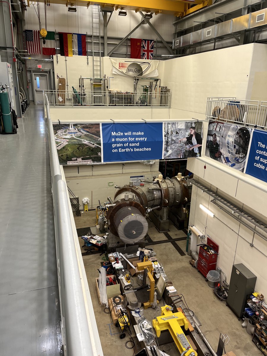 ScottDodelson's tweet photo. Have not seen anything yet here at #Fermilab cooler than #mu2e. The Transport Solenoid beneath the sign conveying just how many #muons will be produced. Amazing! https://t.co/3lKKGylTwO