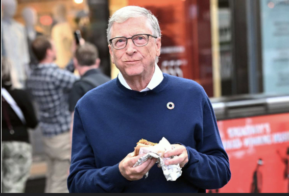 bryan_johnson's tweet photo. Gates peacocking in NY yesterday, downing a hotdog. What do you make of infinite money and poor health choices? https://t.co/2TGy4R5Lve