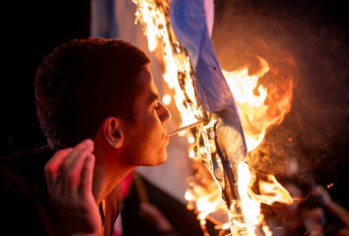 Iranian lights his cigarette on a burning Israel flag. Seen in Tehran last night.