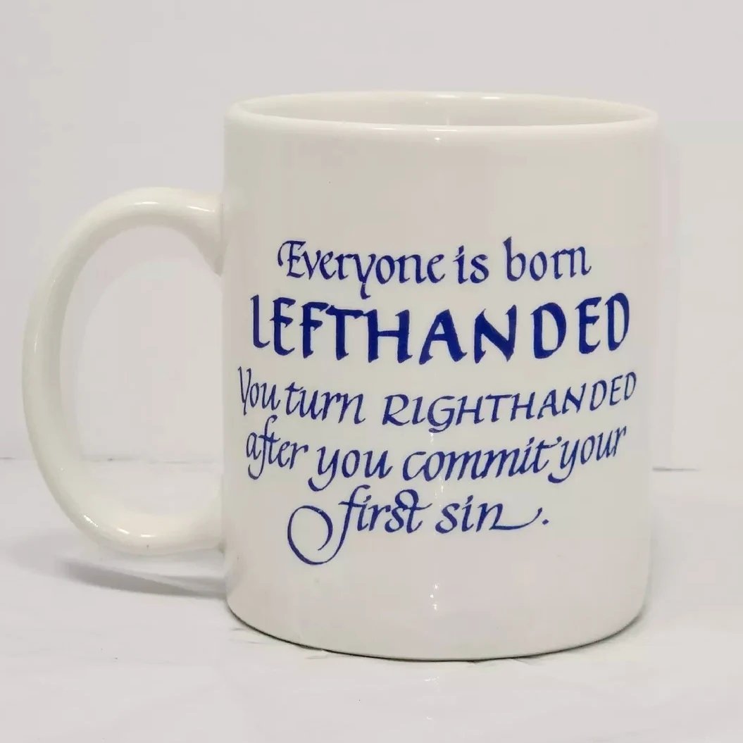 White Pat's Critters mug with lovely blue calligraphy reading "Everyone is born LEFTHANDED you turn RIGHTHANDED after you commit your first sin.". 